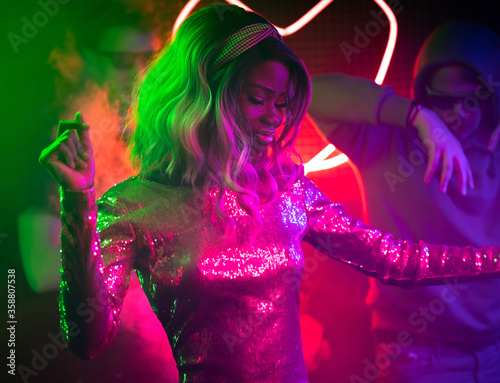 Obraz na płótnie Young African American woman dancing in disco club among her fans
