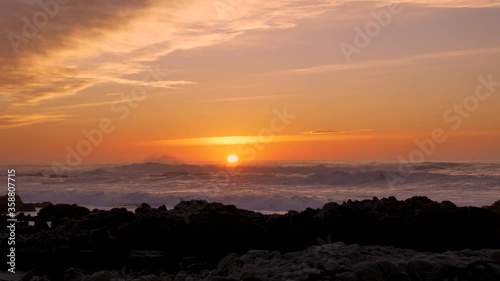 Slow motion Pacific Ocean big Waves rolling in and break on a rocky coast under a sunset sky at Pacific Grove, California on the Monterey Peninsula at stormy weather