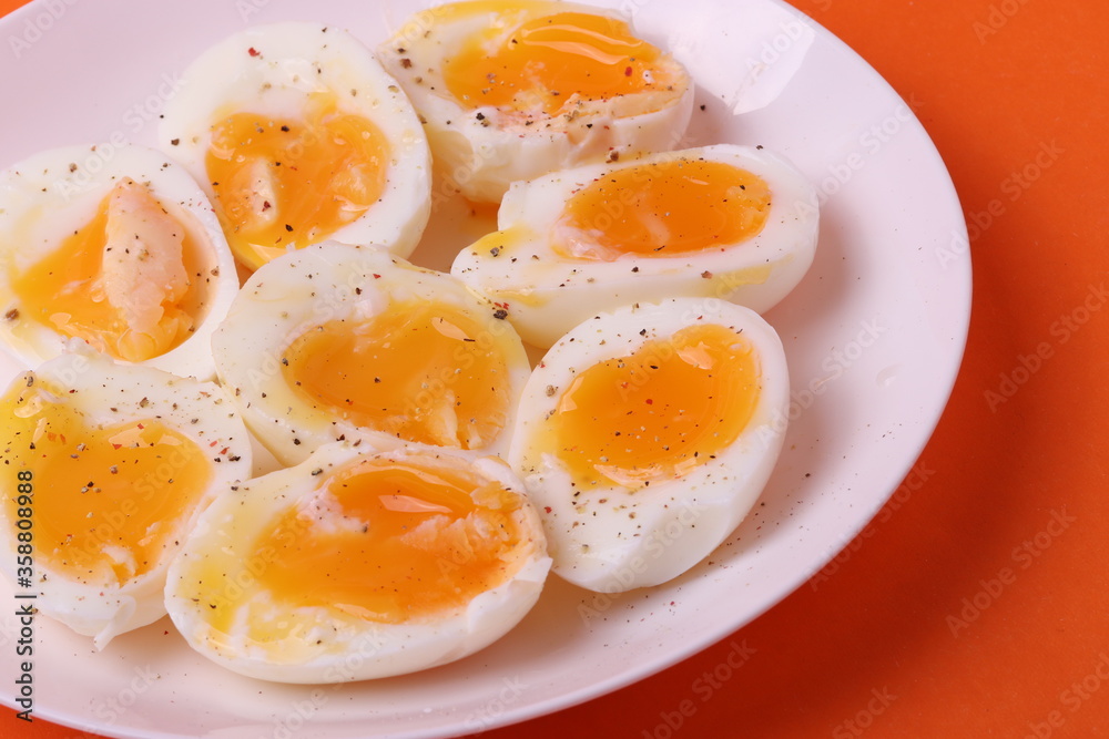 soft-boiled sunny side up halves of chicken eggs on the white plate bright orange background. close up shot. minimalism concept soft-boiled sunny side up halves of chicken eggs on the white plate bright orange background. close up shot. minimalism concept