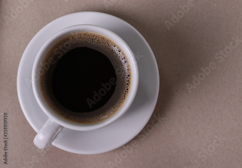 black espresso in a white ceramic cup and a saucer on the light beige background. close up shot, minimalism style