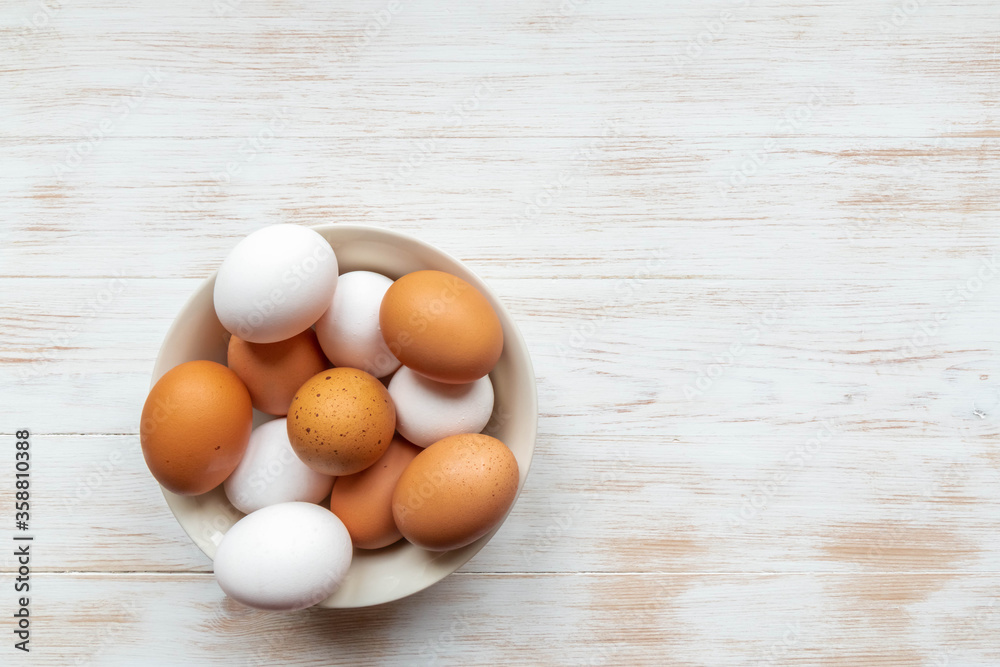 Free-range organic white and brown eggs in bowl on wood background with copy space Free-range organic white and brown eggs in bowl on wood background with copy space