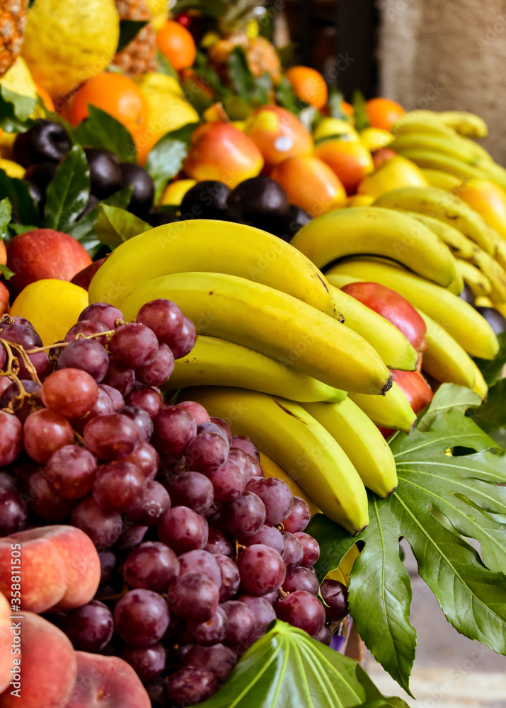 Supply of assorted fresh fruits (bananas, black grapes, flat peaches, ...) displayed for sale Supply of assorted fresh fruits (bananas, black grapes, flat peaches, ...) displayed for sale
