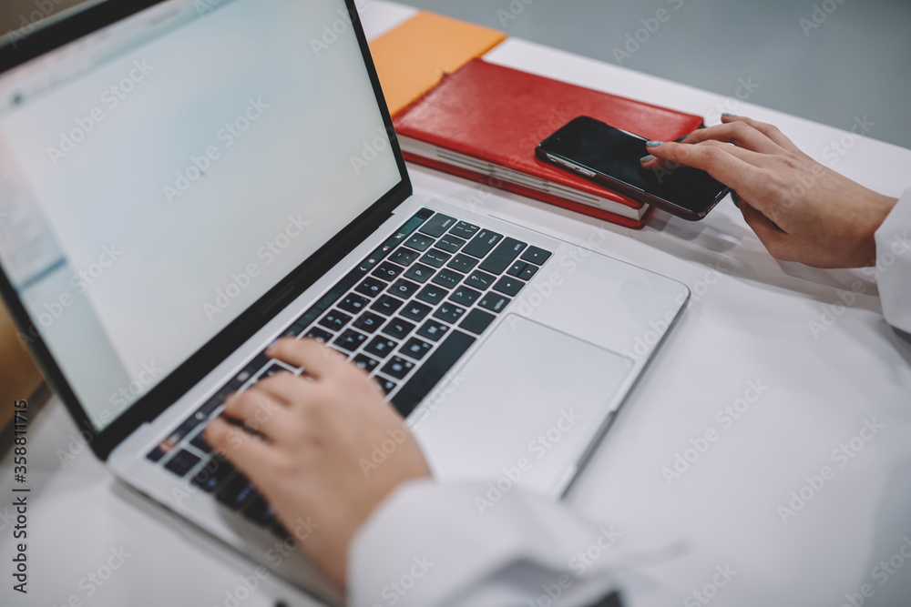 Selective focus on female student hands keyboarding information on laptop computer connected to wifi during preparation to exams, cropped image of woman making presentation on netbook sitting at table Selective focus on female student hands keyboarding information on laptop computer connected to wifi during preparation to exams, cropped image of woman making presentation on netbook sitting at table