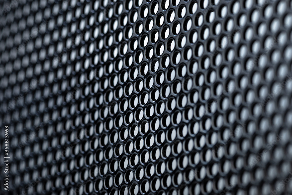 Macro shot of a black metal surface with round holes, gray background. Macro shot of a black metal surface with round holes, gray background.
