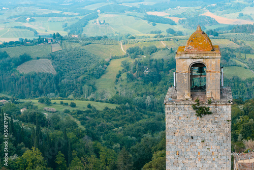 Fotografía The top of Torre Rognosa with typical Tuscan countryside in the background seen from the top of the Great Tower (Torre Grossa), San Gimignano, Italy