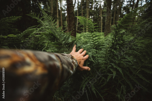 Close up of explorer male hand in green rainy wilderness forest.Survival travel,lifestyle concept.	