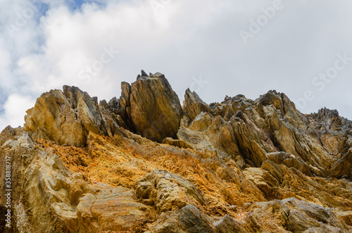 Fototapeta Naklejka Na Ścianę i Meble -  Yellow rock mountain against cloudy sky background. Rock wall in Poland near Colored Lakes. Huge rock mountain textured surface.
