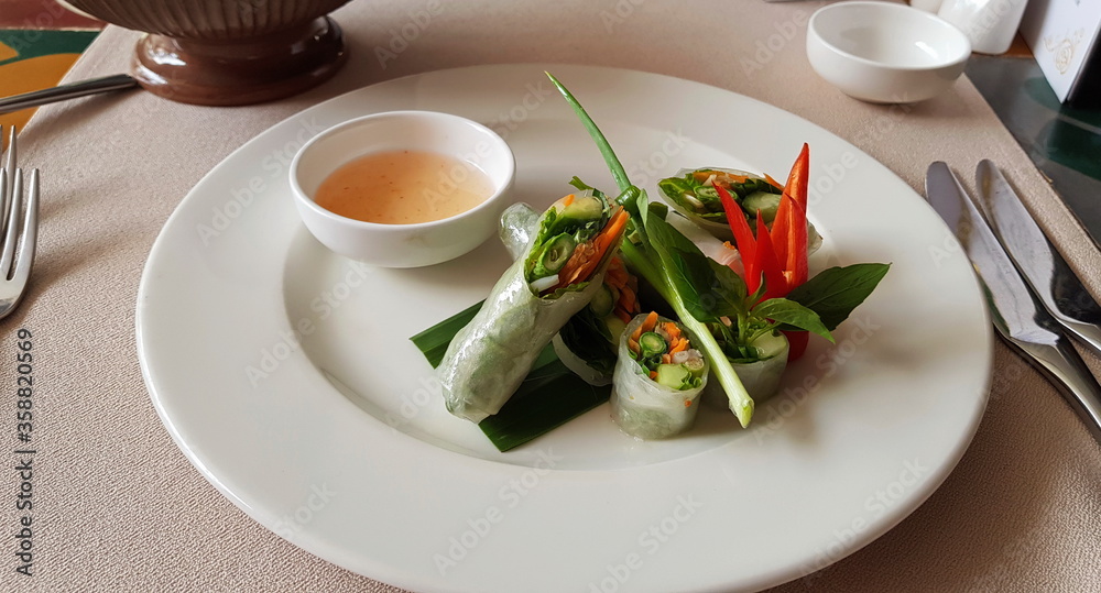 Vegetables rolls from rice base on white plate. Green onion and red pepper, sauce. Vegetables rolls from rice base on white plate. Green onion and red pepper, sauce.