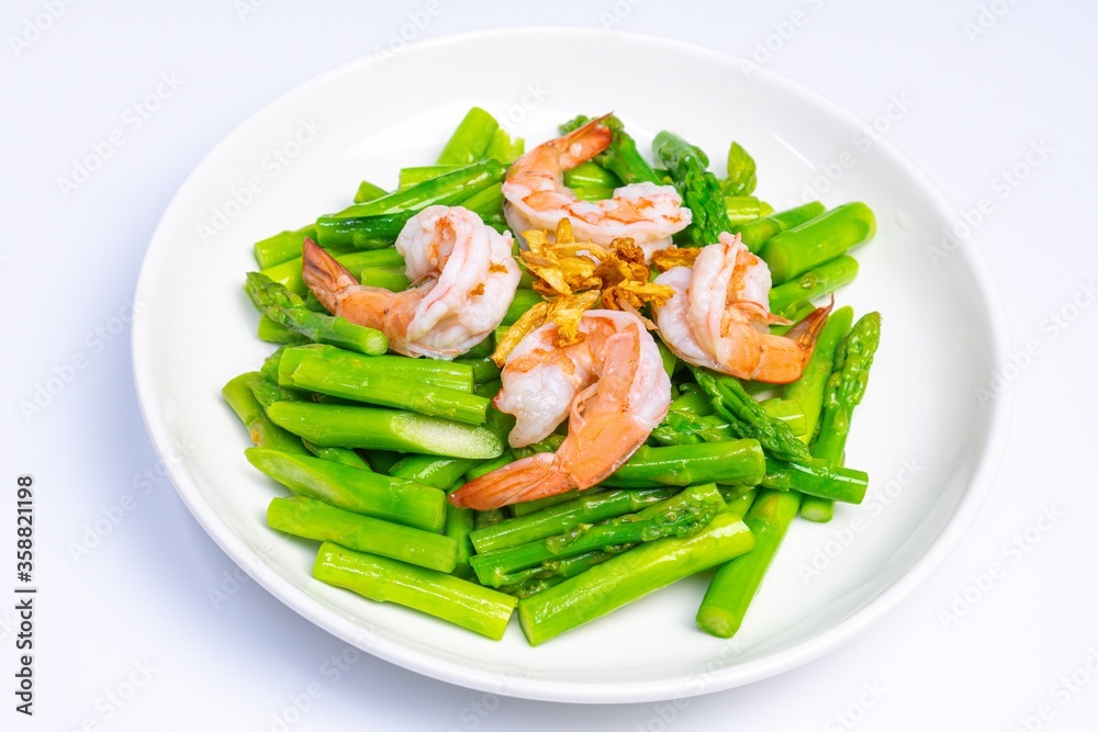 Stirred fried asparagus with shrimp served on white plate isolated on white background. famous thai food in thailand. popular food in Asia. Stirred fried asparagus with shrimp served on white plate isolated on white background. famous thai food in thailand. popular food in Asia.