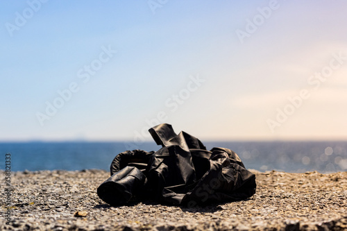 black rubber gloves on rock at the beach with sunlight on right side. sea ​​and beach pollution.