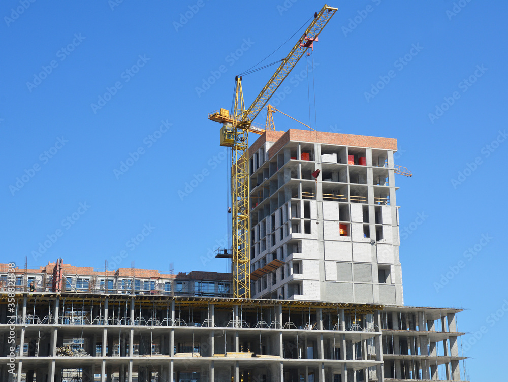 Construction of a new office building, shopping center, mall with a tower crane against blue sky.