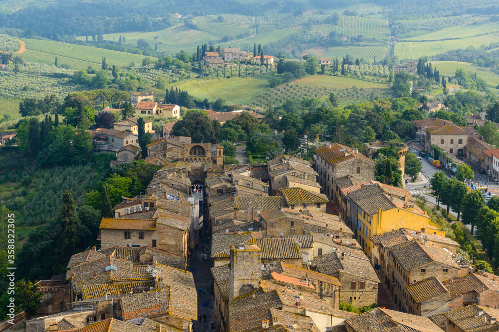 Rooftops of old town of San Gimignano and Via S. Giovanni ending with Porta San Giovanni seen from the Great Tower (Torre Grossa), San Gimignano, Italy.