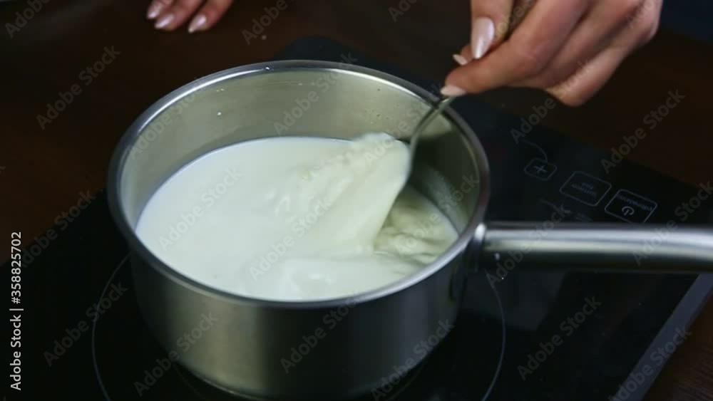 slow motion closeup on hands by spoon stir milk with sugar in metal saucepan
