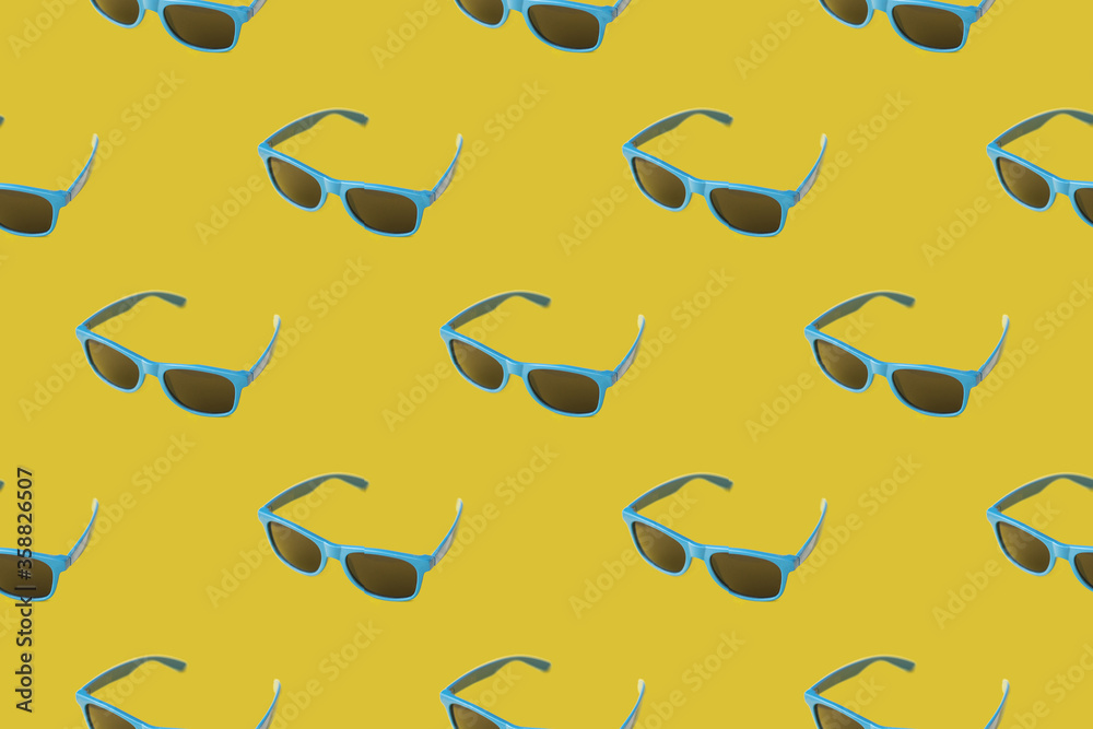 Pattern with summer blue sunglasses on a yellow background with black lenses. Summer minimalism Pattern with summer blue sunglasses on a yellow background with black lenses. Summer minimalism