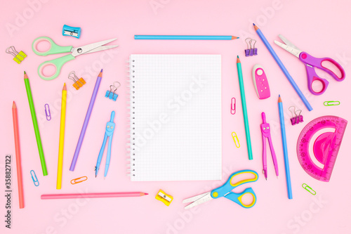 Back to school concept on pink background. School supplies and open notebook on pastel pink background 
