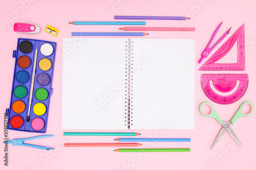 Back to school concept on pink background. School supplies and open notebook on pastel pink background 