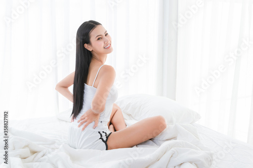 Asian people are beautiful, charming Stretching in the morning on the bed in a white bedroom.