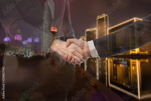 Teamwork, partnership and success concept. Double exposure of business handshake for successful of investment deal and city night background.