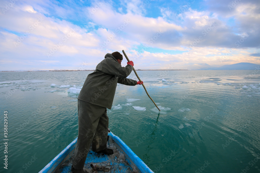 A fisher on water, fishing in harsh conditions, fishing in winter, fisher on water A fisher on water, fishing in harsh conditions, fishing in winter, fisher on water