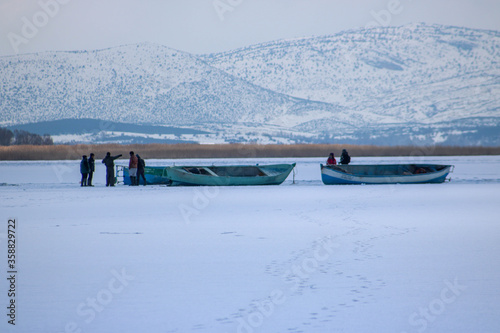 Fishing boats and fishers on a frozen lake, fishing industry in winter, fishing industry in snow