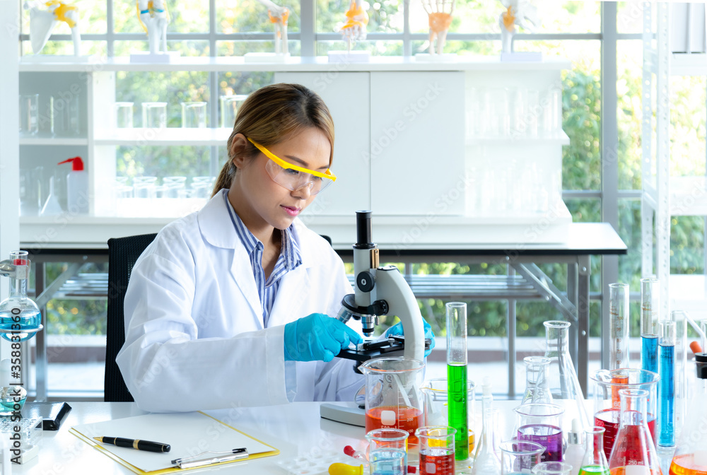 Young scientist looking through a microscope in a laboratory. Health care researchers working in life science laboratory Young scientist looking through a microscope in a laboratory. Health care researchers working in life science laboratory