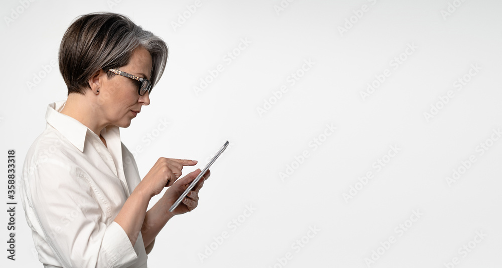 Gray-haired Caucasian businesswoman typing on tablet computer on white background. Horizontal template for ad banner with textspase at right. Gray-haired Caucasian businesswoman typing on tablet computer on white background. Horizontal template for ad banner with textspase at right.