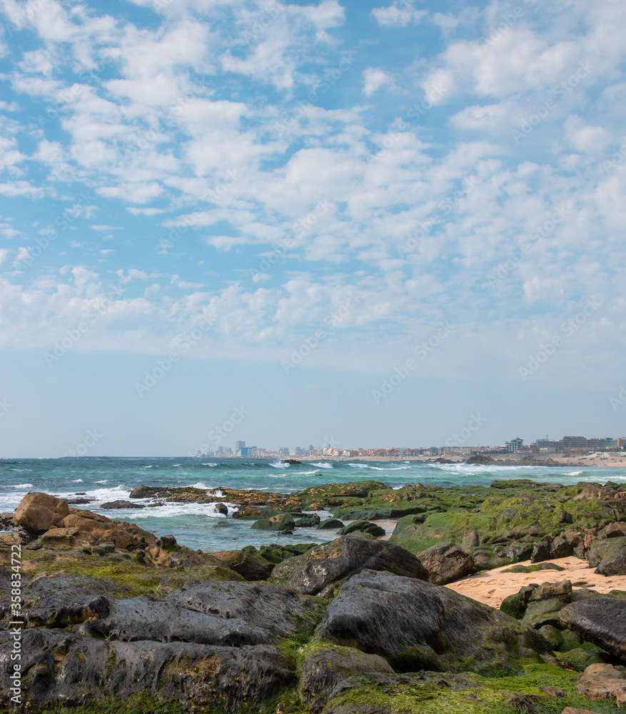 Landscape of the beach in Póvoa de Varzim, rocky beach and city in the background in the image. Appealing and stunning beach north of Portugal.