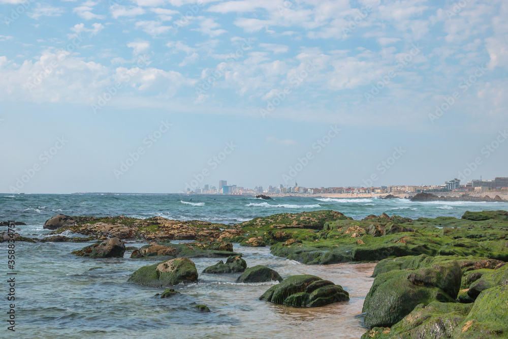 Landscape of the beach in Póvoa de Varzim, rocky beach and city in the background in the image. Appealing and stunning beach north of Portugal. Landscape of the beach in Póvoa de Varzim, rocky beach and city in the background in the image. Appealing and stunning beach north of Portugal.