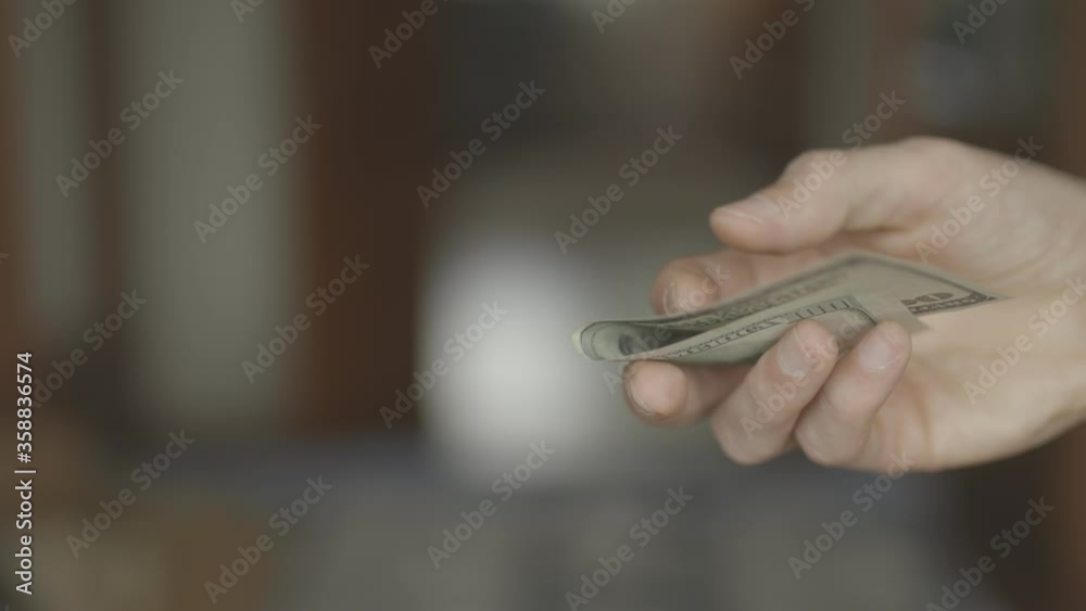 A girl gives dollars to a man's hand. Money. A close-up of a female hand gives a lot of dollar bills to a man. A girl gives dollars to a man's hand. Money. A close-up of a female hand gives a lot of dollar bills to a man.