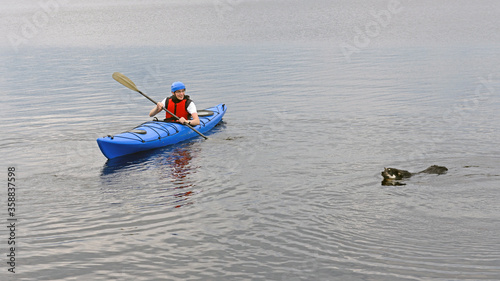 Young man kayaking with dog on big lake. Summer. Finnish Lapland photo