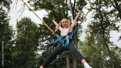 Teenage girl jumping on the trampoline bungee.