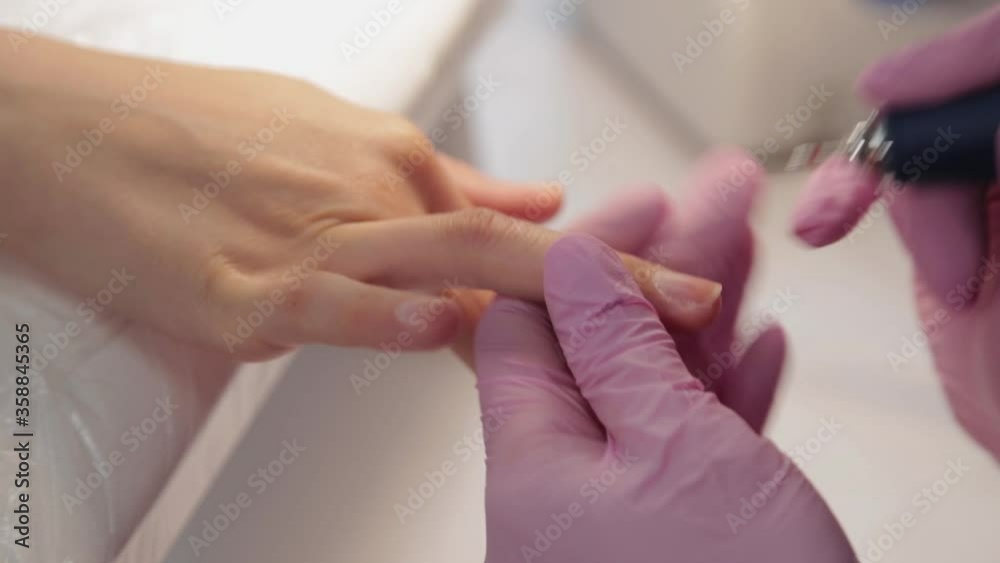 Manicurist cuts nails with a machine to a client in a manicure salon. Manicurist cuts nails with a machine to a client in a manicure salon.
