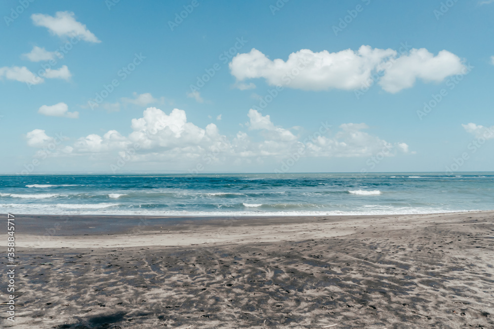 large waves crashing in sand beach rocks on bali island