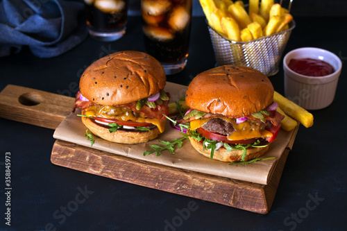 Homemade beef burgers and french fries on dark background. Horizontal image