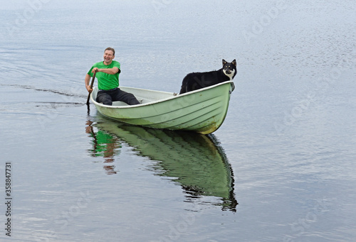 Obraz na płótnie Man with dog on boat on lake. Taivalkoski, Finnish Lapland