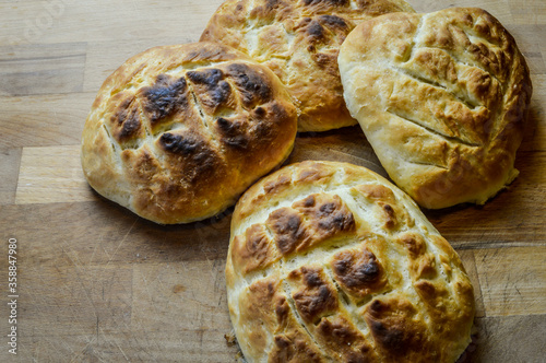 Little italian focaccia breads homemade and freshly cooked on a wooden table close up. The focaccia is a traditional italian oven baked flat bread. photo