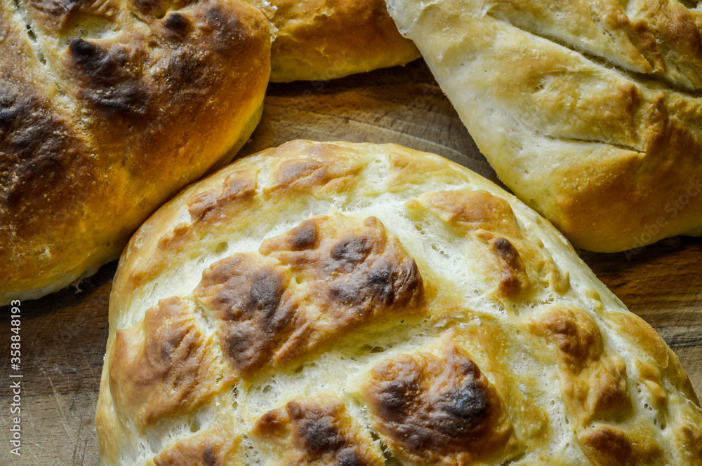 Little italian focaccia breads homemade and freshly cooked on a wooden table close up. The focaccia is a traditional italian oven baked flat bread.