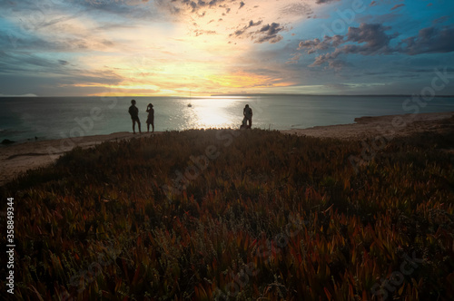Group of friends watching the sunset at a beach of Formentera island, Mediterranean sea, Spain