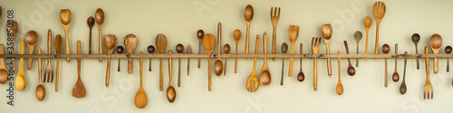 Wooden spoon, fork and kitchen tools insert in wood shoulder pole and hanging on the wall. Background and banner concepts.