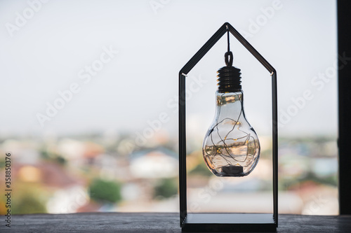Light bulb with house cage on the table, a symbol for construction, Creative light bulb idea, power energy or business idea concept ecology, loan, mortgage, property or home. © sommart