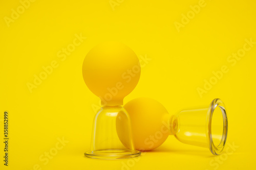 yellow vacuum jars for massage against cellulite on a yellow background