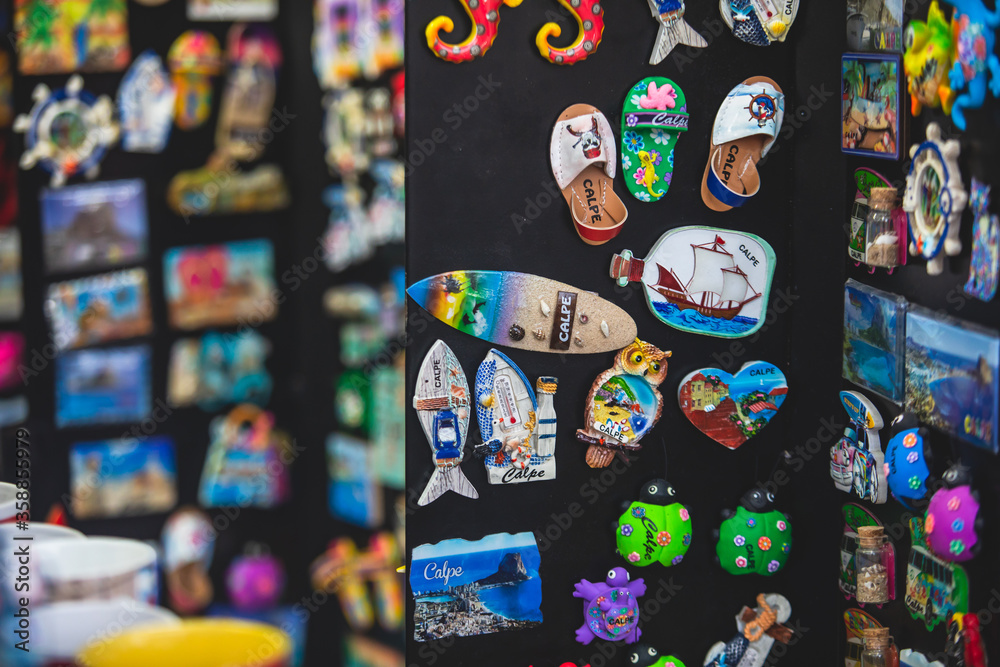 View of traditional tourist souvenirs and gifts from Calpe, Calp, Alicante, Valencia with toys, fridge magnets with and key ring keychain, in local vendor souvenir shop