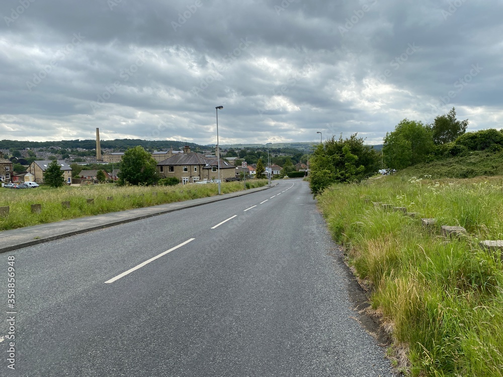 Main road into Baildon, with grass verge and houses,