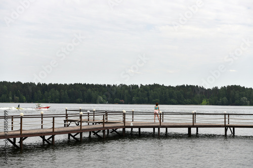 woman looks at sports exercises on the river from the pier © константин константи