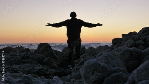 Young men warrior monk practicing silhouette tai chi karate kung Fu on the rocky stones horizon at sunset or sunrise. Art of self-defense. Silhouette on a background of dramatic epic waves