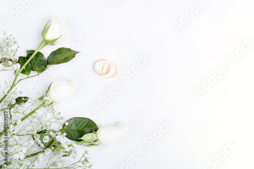 pink rose and wedding rings over white background