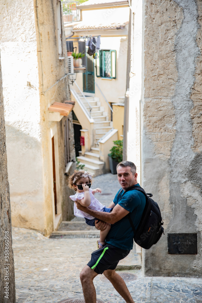 
father and daughter having fun on the streets of an old village called FiumeFreddo, Calabria, Italy