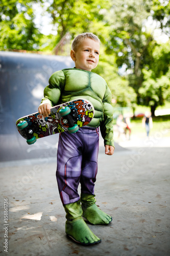 Boy with a skate in a skate park. In a superhero costume.