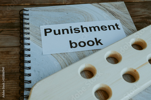 Punishment book. Wooden paddle for spanking on headmaster's or teacher's desk. School corporal punishment. Discipline and spanking in school. Adult role play. Spanking implements, bdsm toys