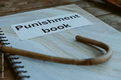 Punishment book. Rattan cane for spanking on headmaster's or teacher's desk. School corporal punishment. Discipline and spanking in school. Adult role play. Spanking implements, bdsm toys